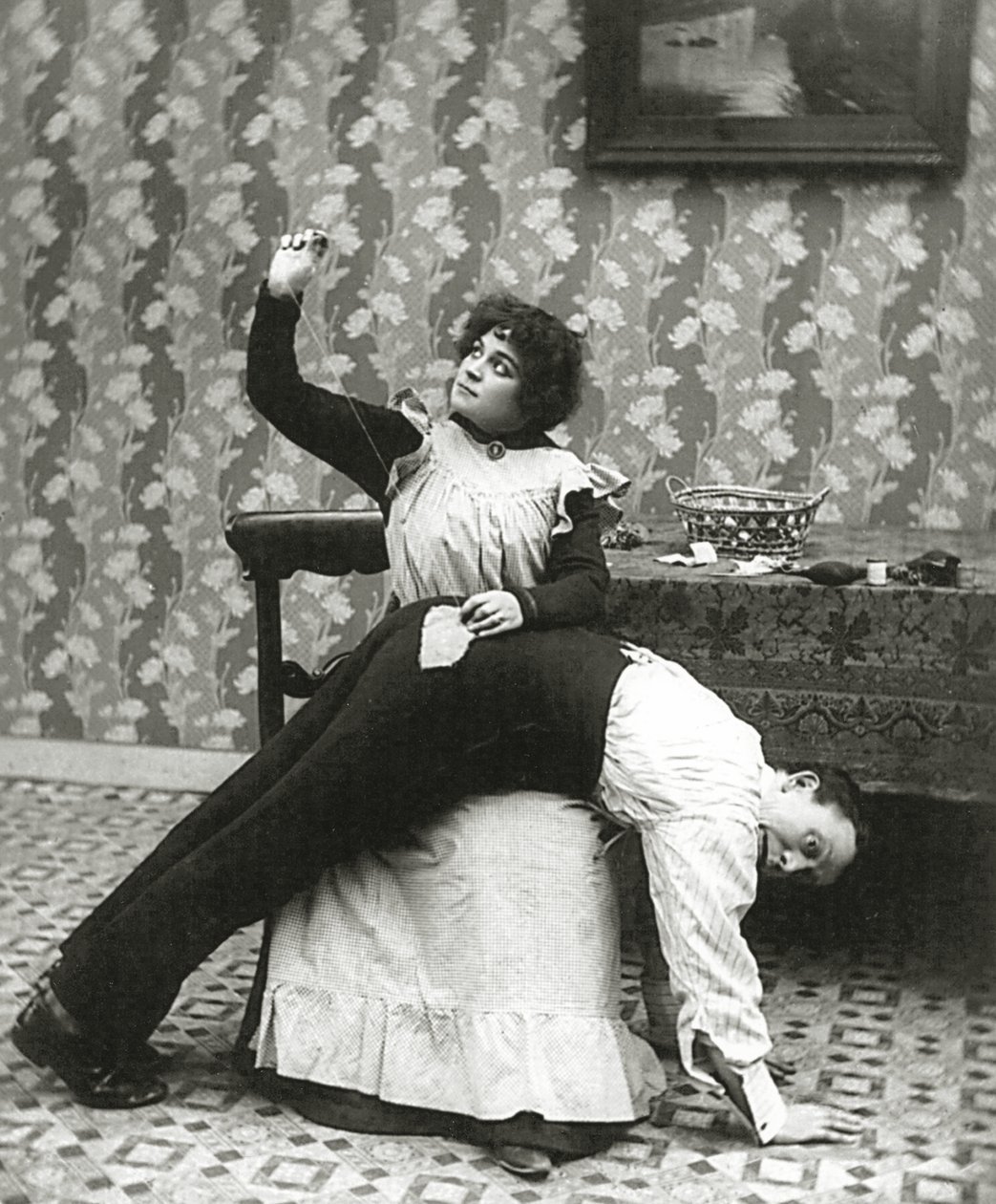 Mujer cosiendo un desgarro en los pantalones de un hombre, c.1895 de American Photographer