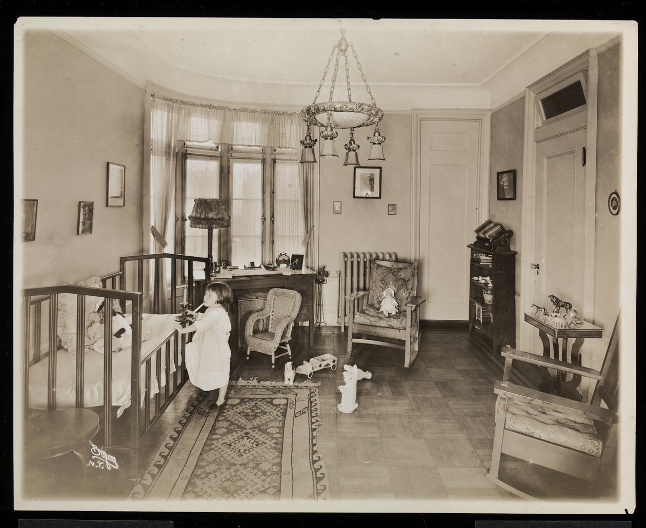 Una niña sosteniendo una vela, subiendo a una cuna, en un dormitorio de la residencia de A.C. Cronin, 1915-16 de Byron Company