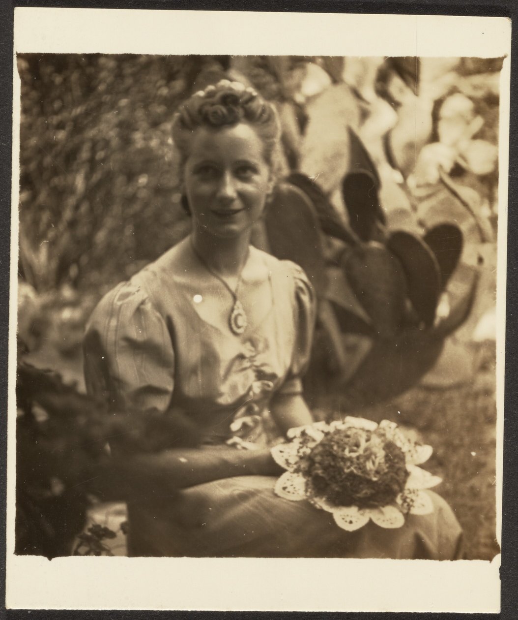 [Mujer con ramo de flores sentada ante un cactus] de Louis Fleckenstein