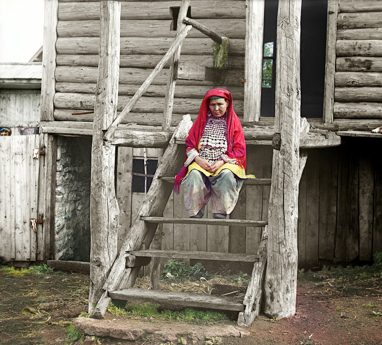 Mujer Bashkir con traje folclórico sentada en las escaleras de su casa de madera, Montes Urales, Imperio Ruso, 1910 de Sergey Prokudin Gorsky