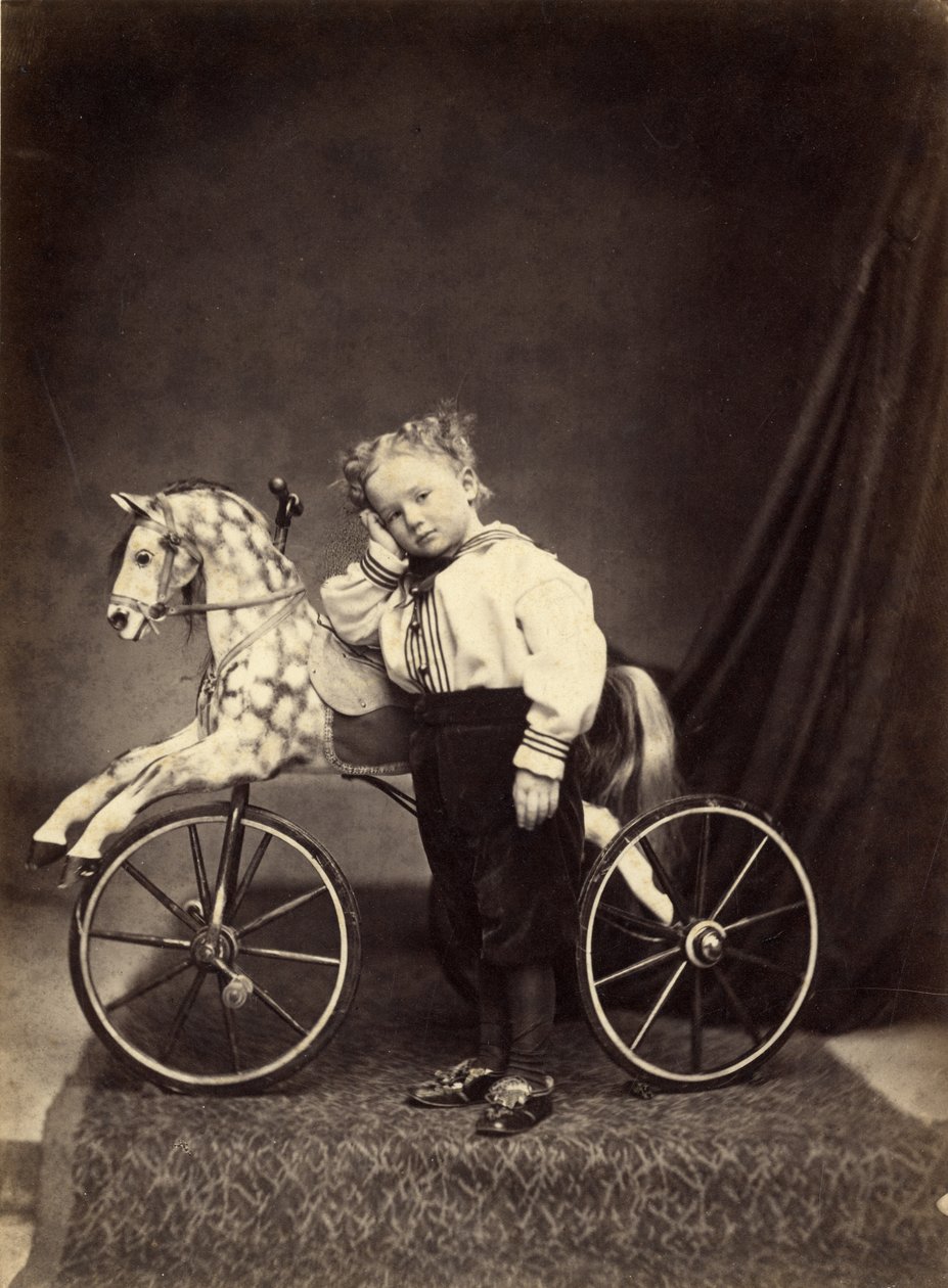 Niño pequeño junto a su caballo montado como un triciclo, 1860s de T. Seed