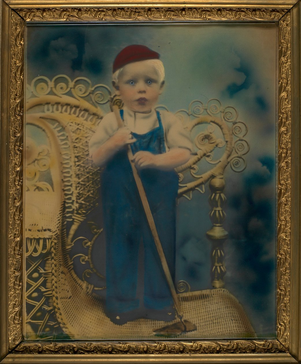 Niño de pie en una silla de mimbre de Unidentified