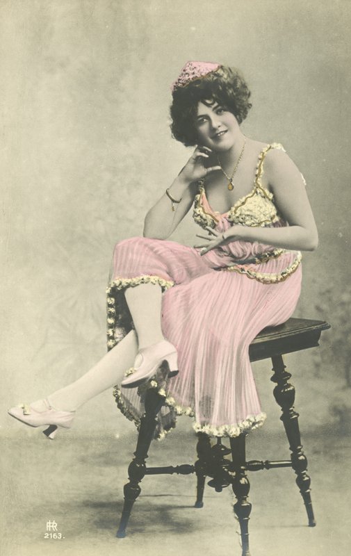 Actriz con bonita sonrisa, en vestido rosa sentada en un taburete de French Photographer
